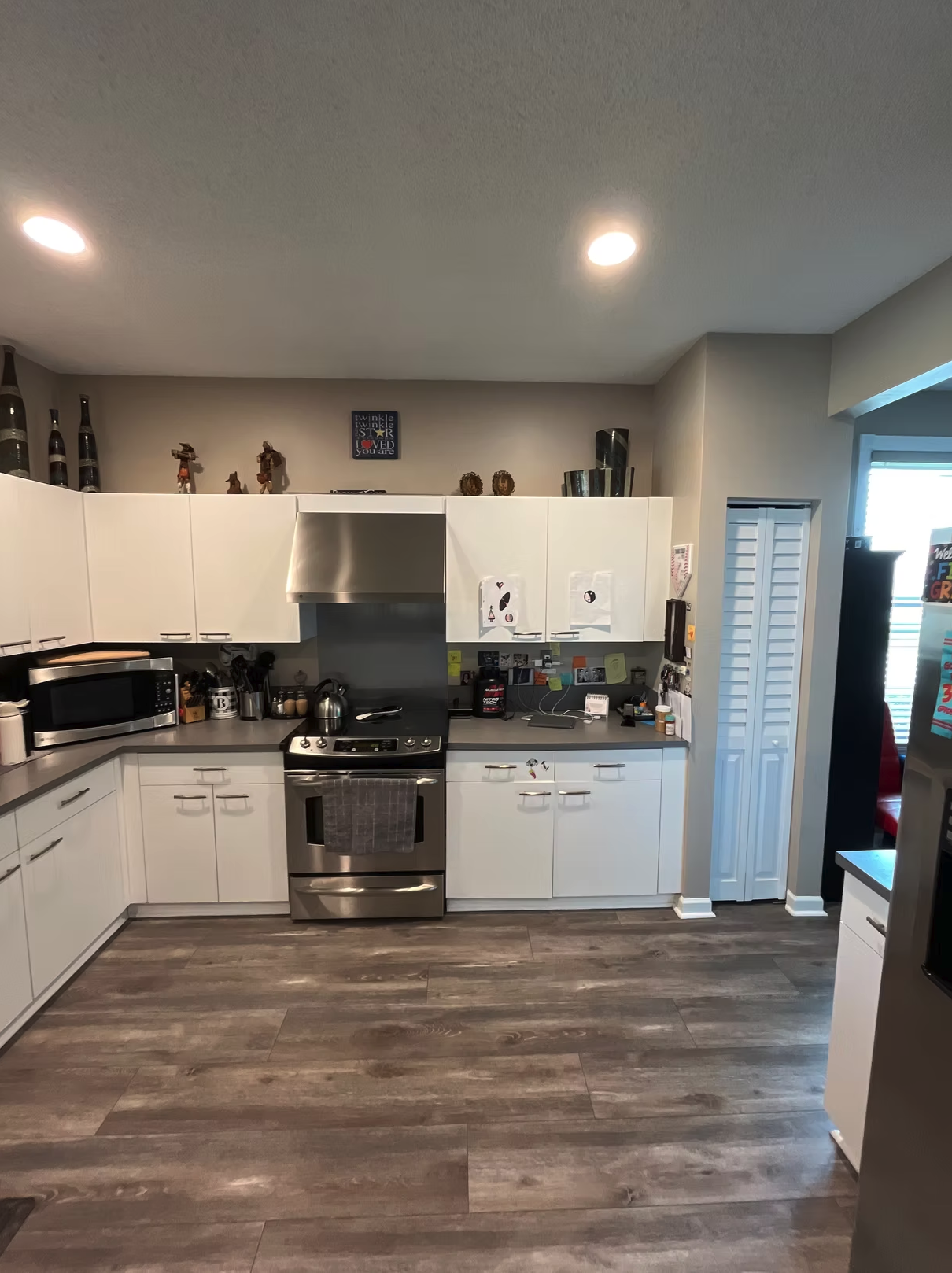 Modern white kitchen with stainless steel appliances and wood-look flooring