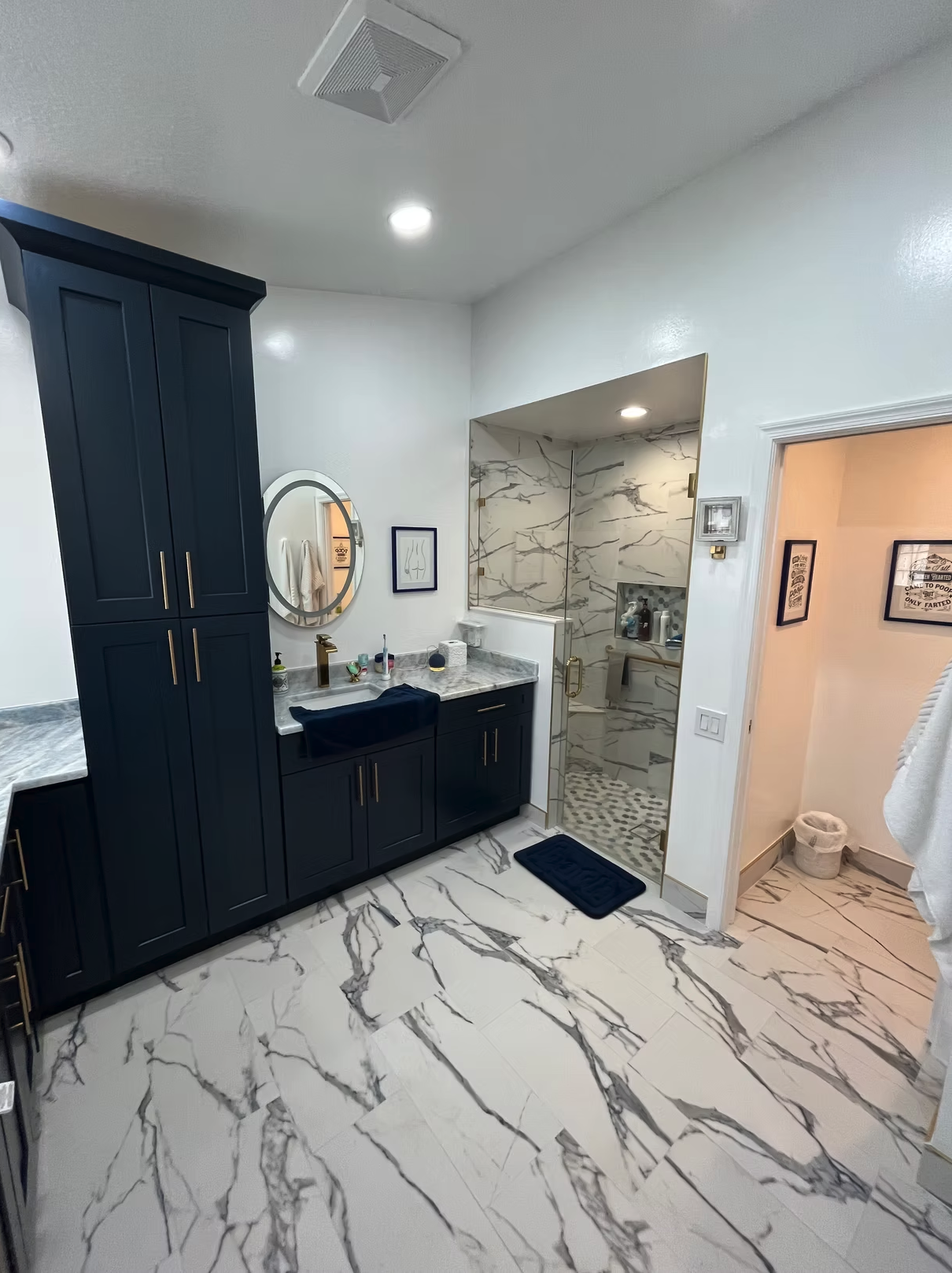 Modern bathroom with marble floors, black vanity, and glass shower