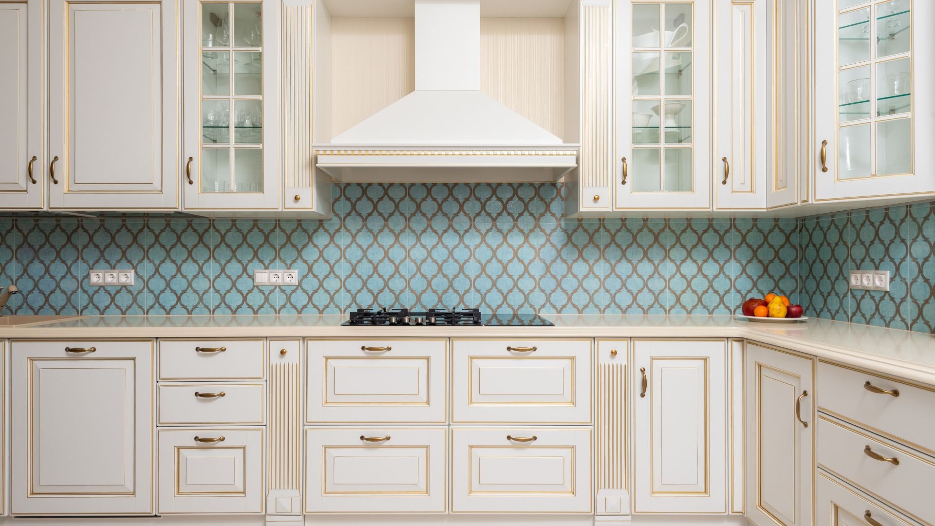 Elegant white kitchen with blue mosaic backsplash and gas stovetop
