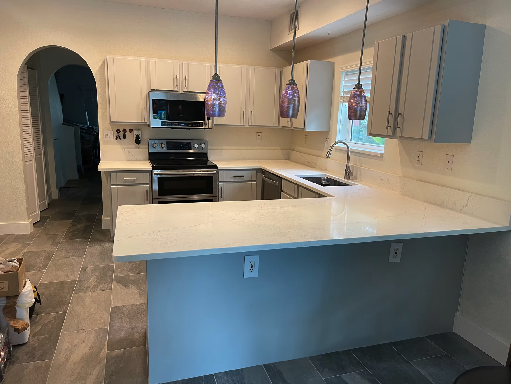 Modern U-shaped kitchen with white cabinets and blue accent island