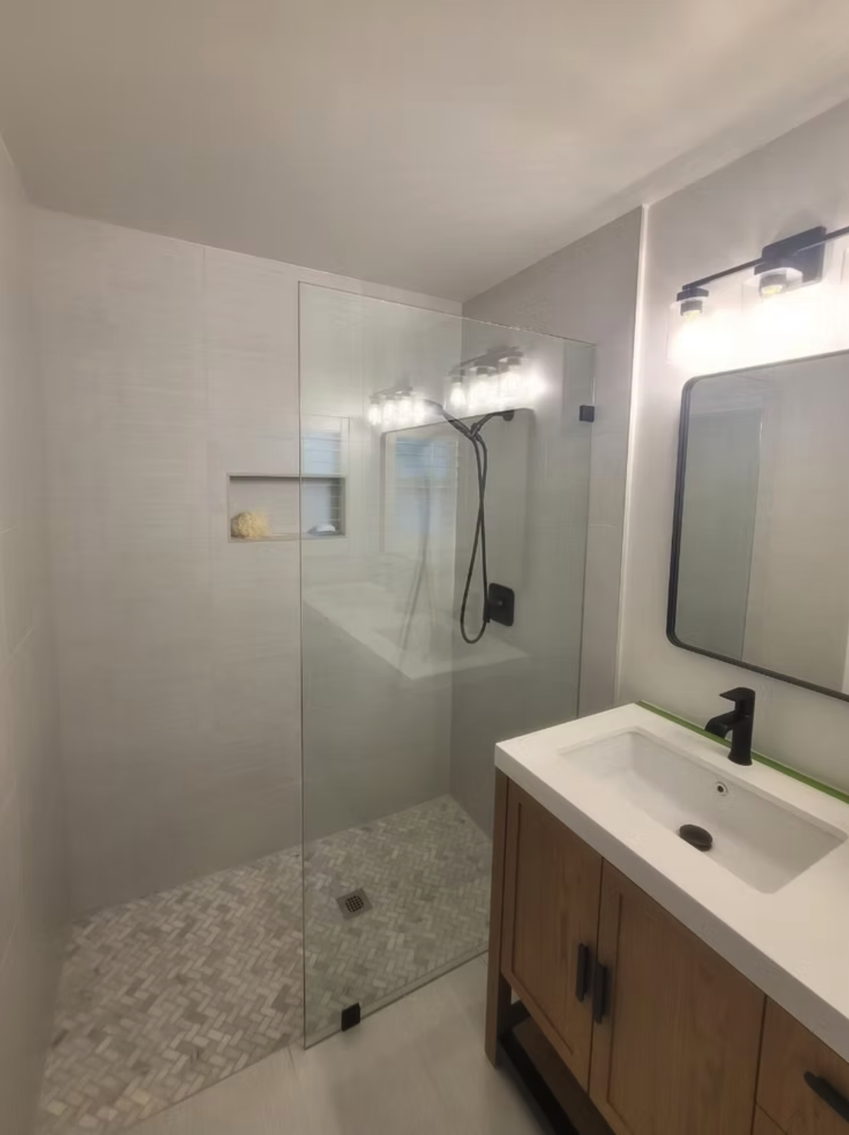Modern bathroom with glass shower, wood vanity, and black fixtures