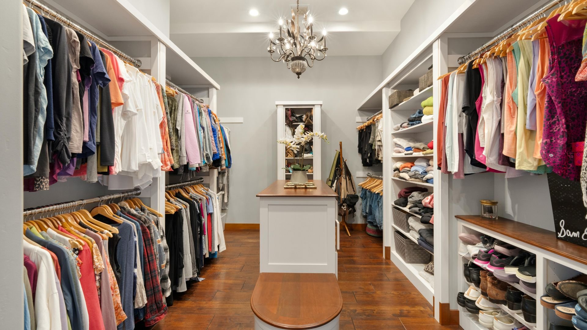 Spacious walk-in closet with colorful clothes, chandelier, and organized shelves