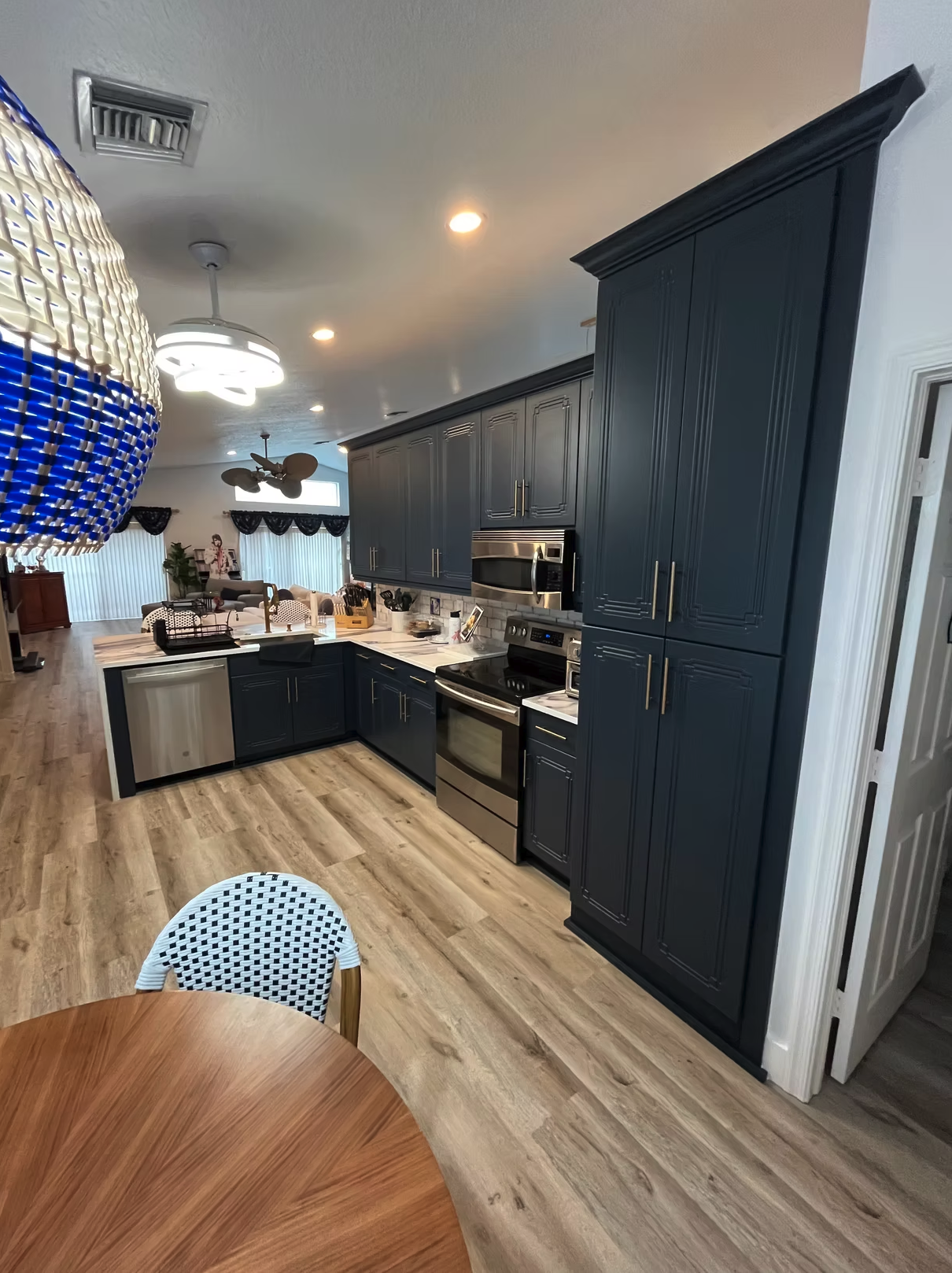 Modern kitchen with navy blue cabinets, marble countertops, and wooden floor
