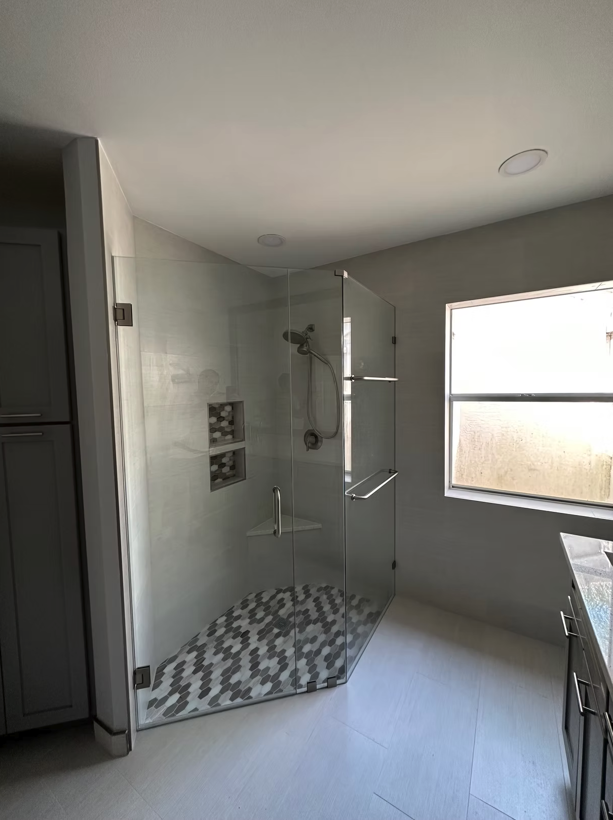 Modern glass shower with hexagonal tile floor and built-in niche