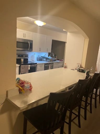 Modern kitchen with white countertop, bar stools, and snack bags