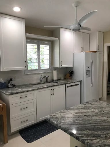 Modern white kitchen with marble countertops and stainless steel appliances