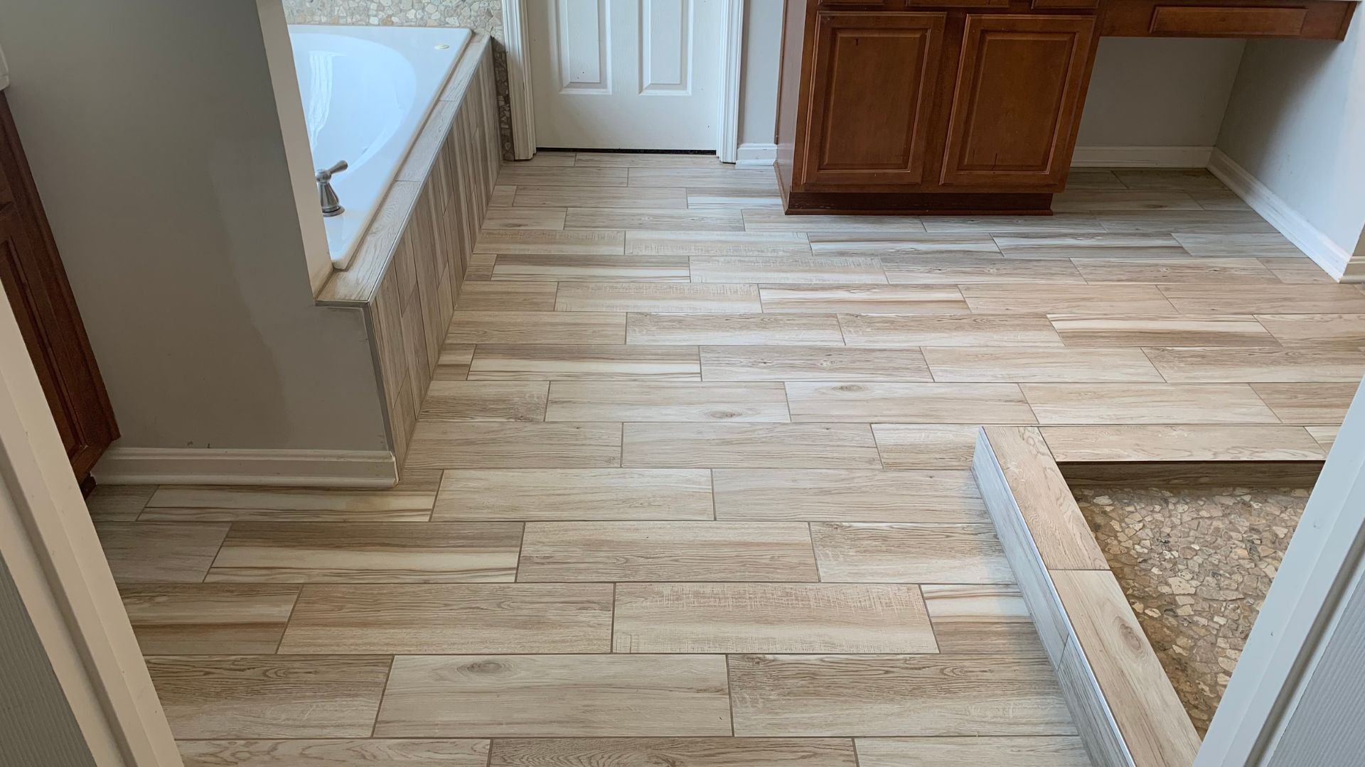 Bathroom with light wood-look tile flooring and wooden cabinets